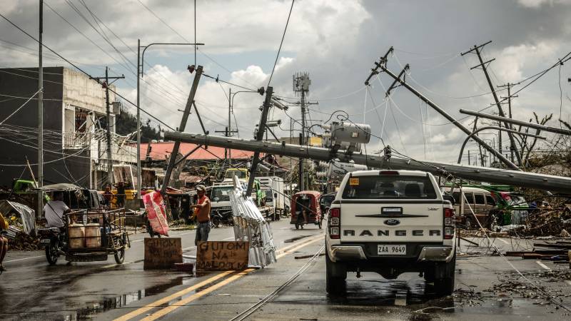 Fallen electric pylons block a road while a sign asking for food (L) is displayed along a road in Surigao City, Surigao del norte province, days after super Typhoon Rai devastated the city. AFP