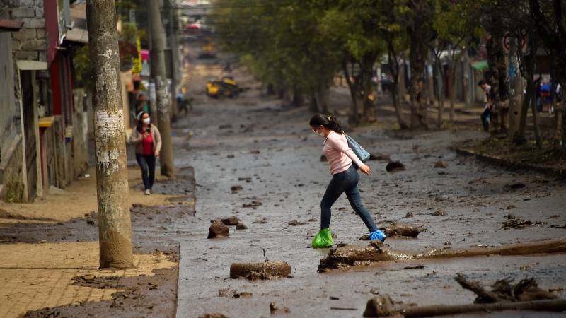 A woman crosses a street covered with mud after a flood in northern Quito. AFP
