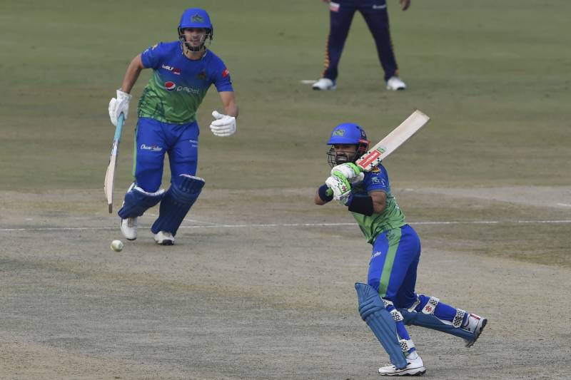 Multan Sultans' captain Mohammad Rizwan (R) plays a shot as teammate Rilee Rossouw watches during the Pakistan Super League (PSL) Twenty20 cricket match between Multan Sultans and Quetta Gladiators at the Gaddafi Cricket Stadium in Lahore