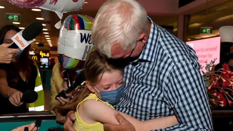 A man hugs his granddaughter Charlotte Roempke upon arriving at Sydney International Airport as Australia reopened its borders for fully vaccinated visa holders, tourists and business travellers. AFP