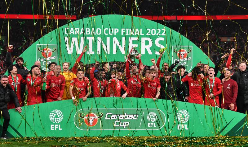 Liverpool\'s English midfielder Jordan Henderson holds up the trophy as Liverpool players celebrate on the pitch after their penalty shoot-out victory in the English League Cup final football match between Chelsea and Liverpool at Wembley Stadium. AFP