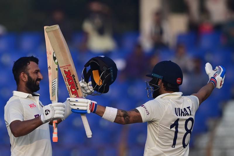 India's Cheteshwar Pujara (L) celebrates after scoring a century (100 runs) with Virat Kohli during the third day of the first cricket Test match between Bangladesh and India at the Zahur Ahmed Chowdhury Stadium in Chittagong. AFP