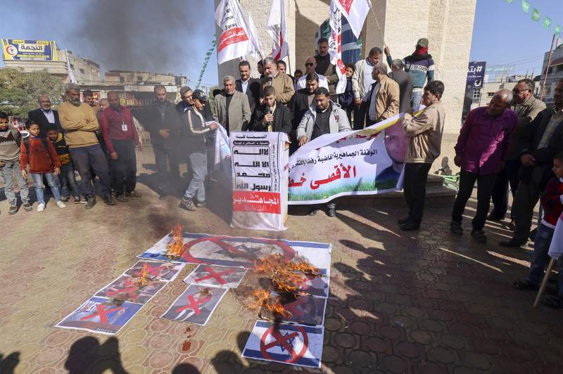Palestinian protesters burn the Israeli flag and defaced posters depicting Israeli Prime Minister-designate Benjamin Netanyahu and Knesset (parliament) members leader of the Religious Zionist Party Bezalel Smotrich, and leader of the far-right Otzma Yehudit (Jewish Power) party Itamar Ben-Gvir, during a rally in Rafah in the southern Gaza Strip, on December 18, 2022, against Israel and in support of Jerusalem's Al-Aqsa Mosque. AFP