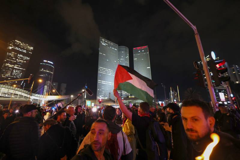 Israeli left wing protesters lift a Palestinian flag during a rally against Prime Minister Benjamin Netanyahu's new hard-right government in the coastal city of Tel Aviv on January 14, 2023. AFP
