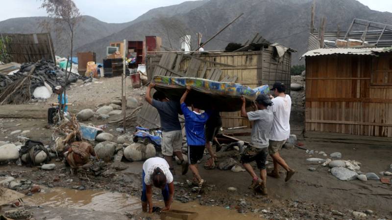 Carmen Manchego looks down at the remnants of homes sticking out of the quagmire of mud that engulfed the Peruvian mining town of Pampaylima.