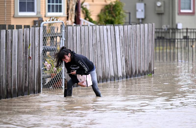 Naomi Rodriguez treads through flood waters to reach her home in the Pajaro area of Watsonville, California on Saturday, March 11, 2023. AFP 
