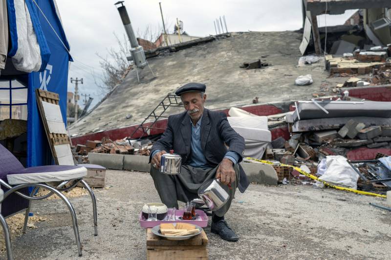 Abuzer Dede, 65-year-old, serves tea as he sits in front of his house after heavy rains in Adiyaman, southeastern Turkey on March 26, 2023, weeks after a 7.8-magnitude earthquake hit the region on February 6, 2023. AFP  