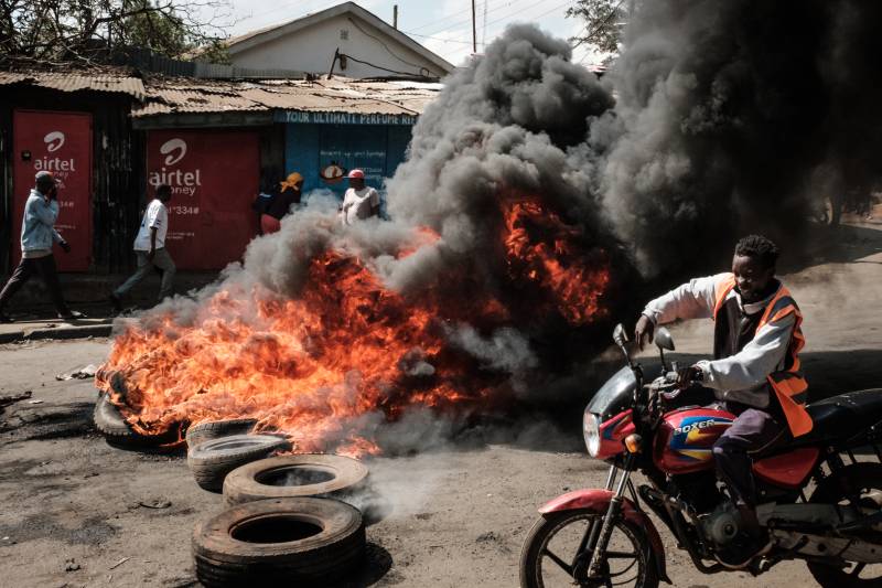 Residents walk past a burning barricade in Kibera, Nairobi, on March 30, 2023 during a protest called by the opposiion coalition 