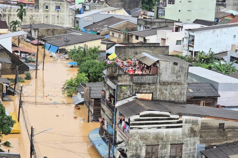 People looking out from residential buildings surrounded by flood waters in Hat Yai, Thailand. AFP